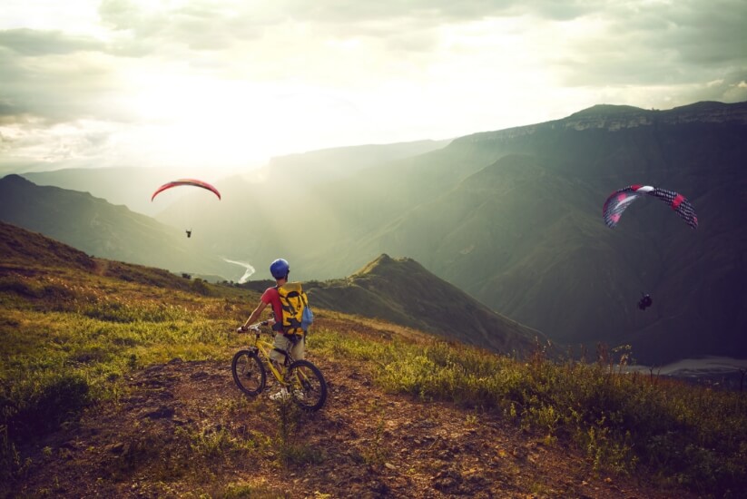 Man on a bicycle observing paragliders in Chicamocha canyon.